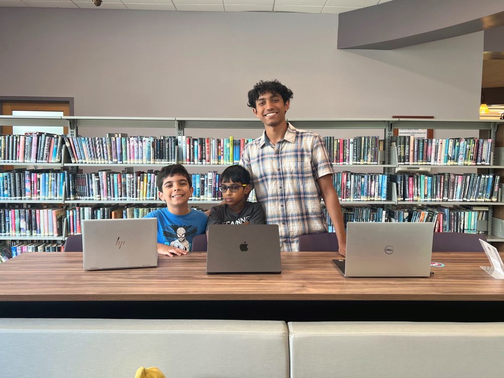 A free AI class at North Wales Area Library, laptops open along a table by the shelves.